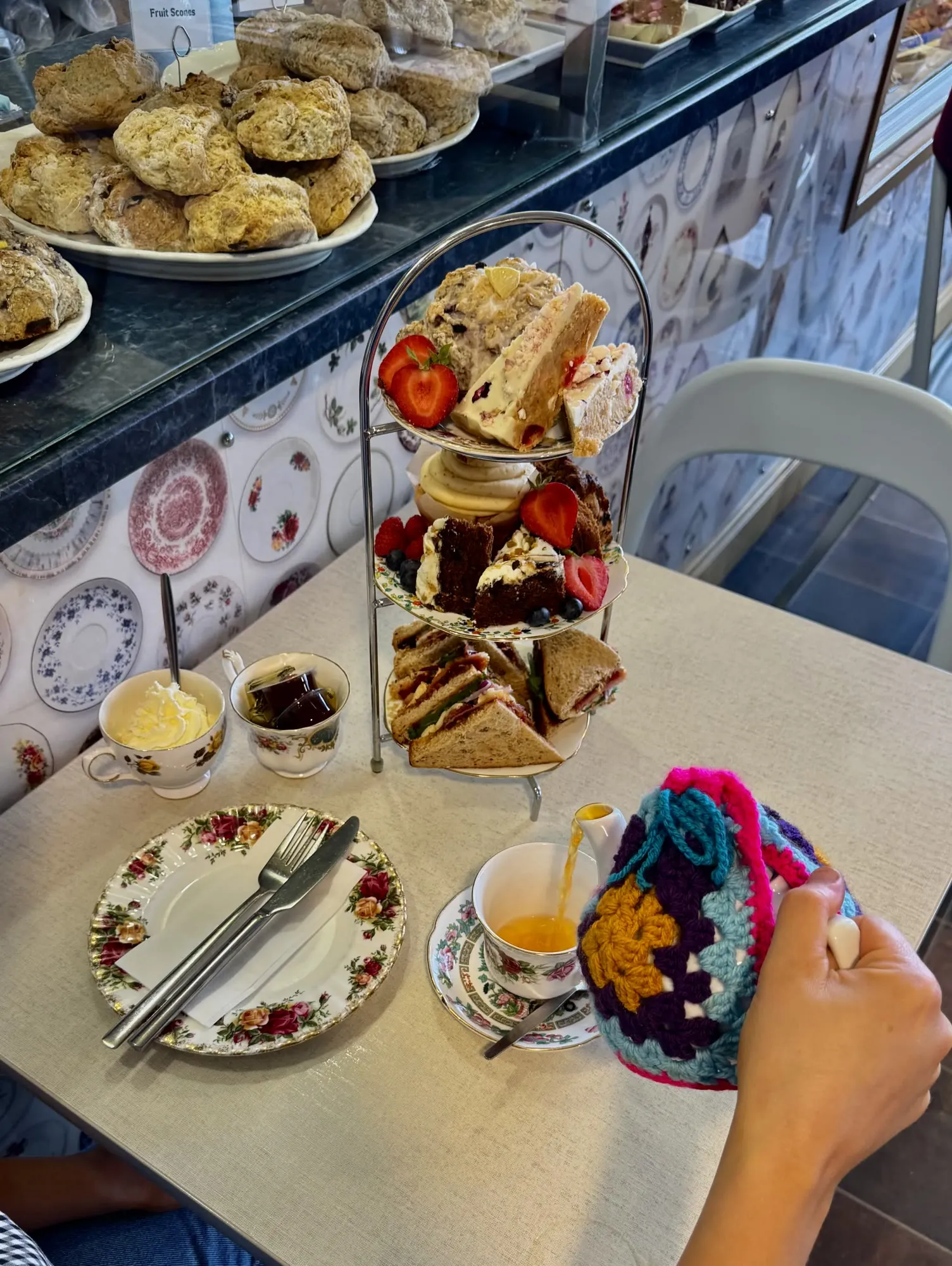 Afternoon tea on a tiered stand with sandwiches, scones and cakes