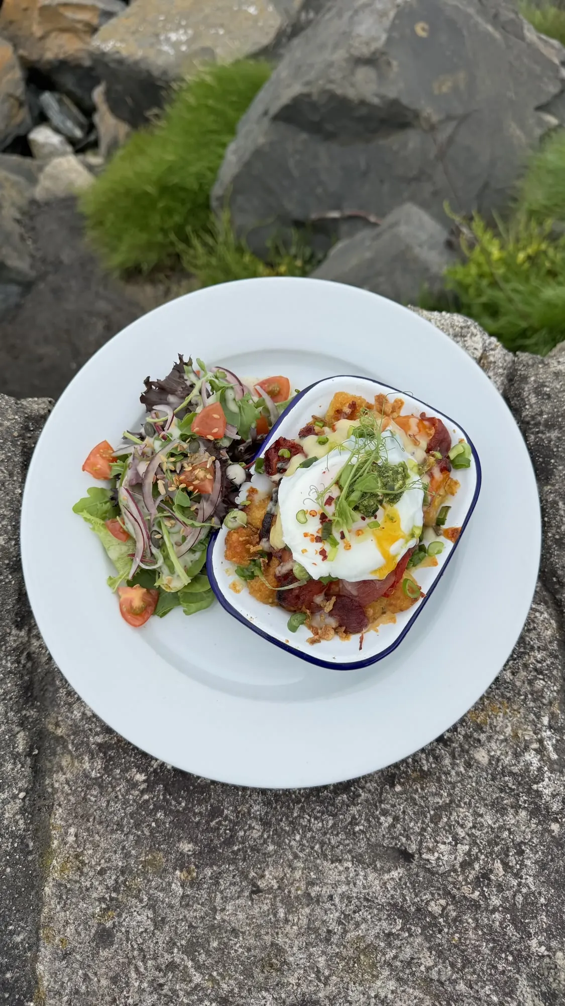 Brunch plate of baked eggs and fresh salad by the sea