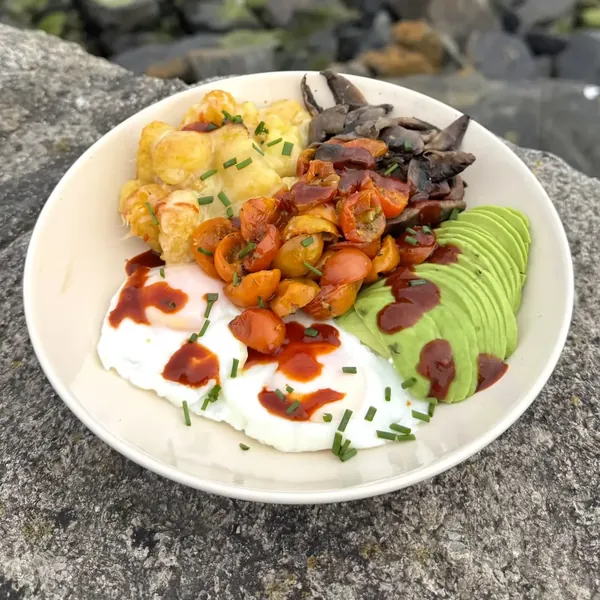 Breakfast bowl with cheesy potatoes, avocado, roast tomatoes, mushrooms and poached eggs