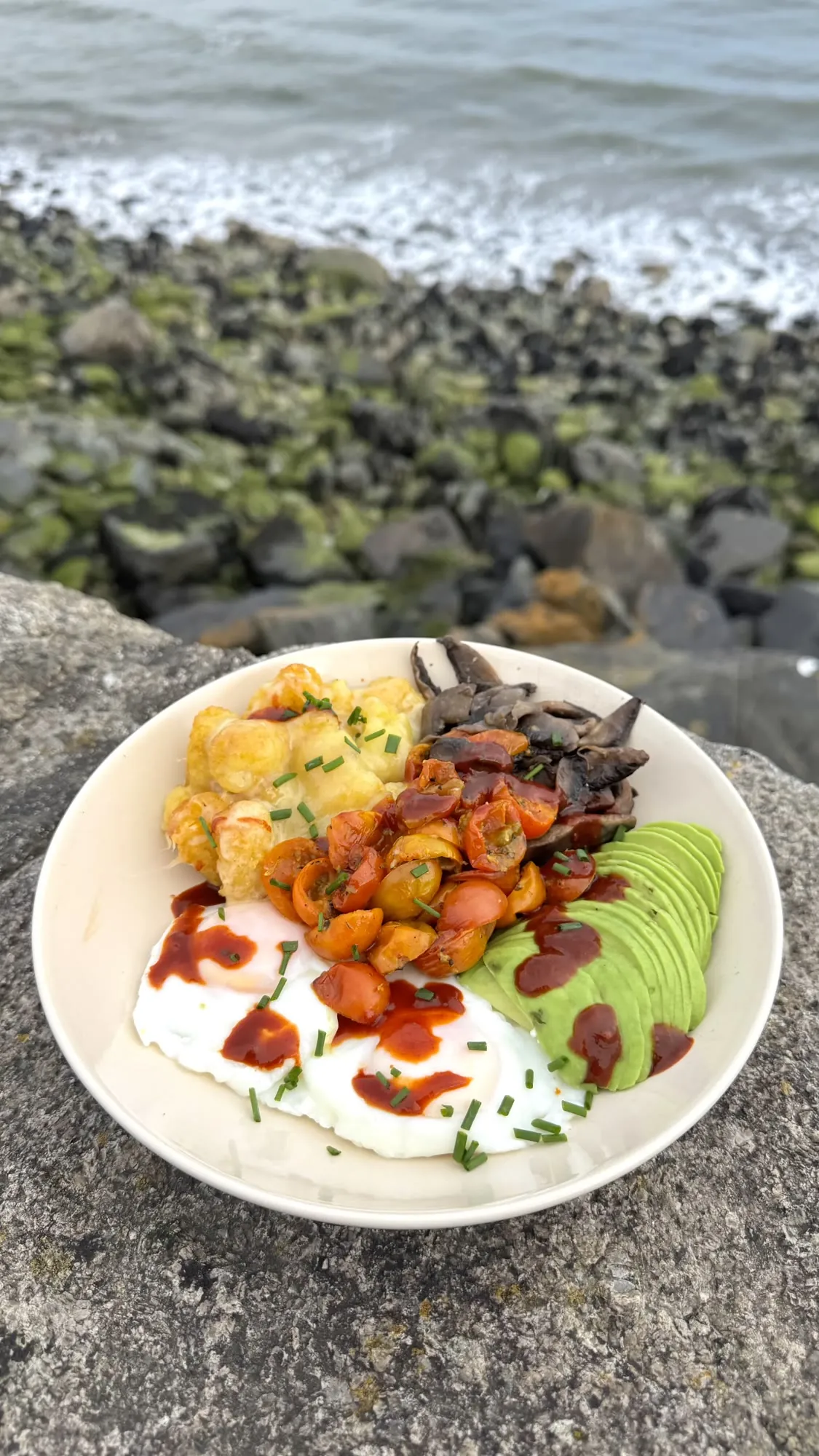 Breakfast bowl with cheesy potatoes, avocado, roast tomatoes, mushrooms and poached eggs