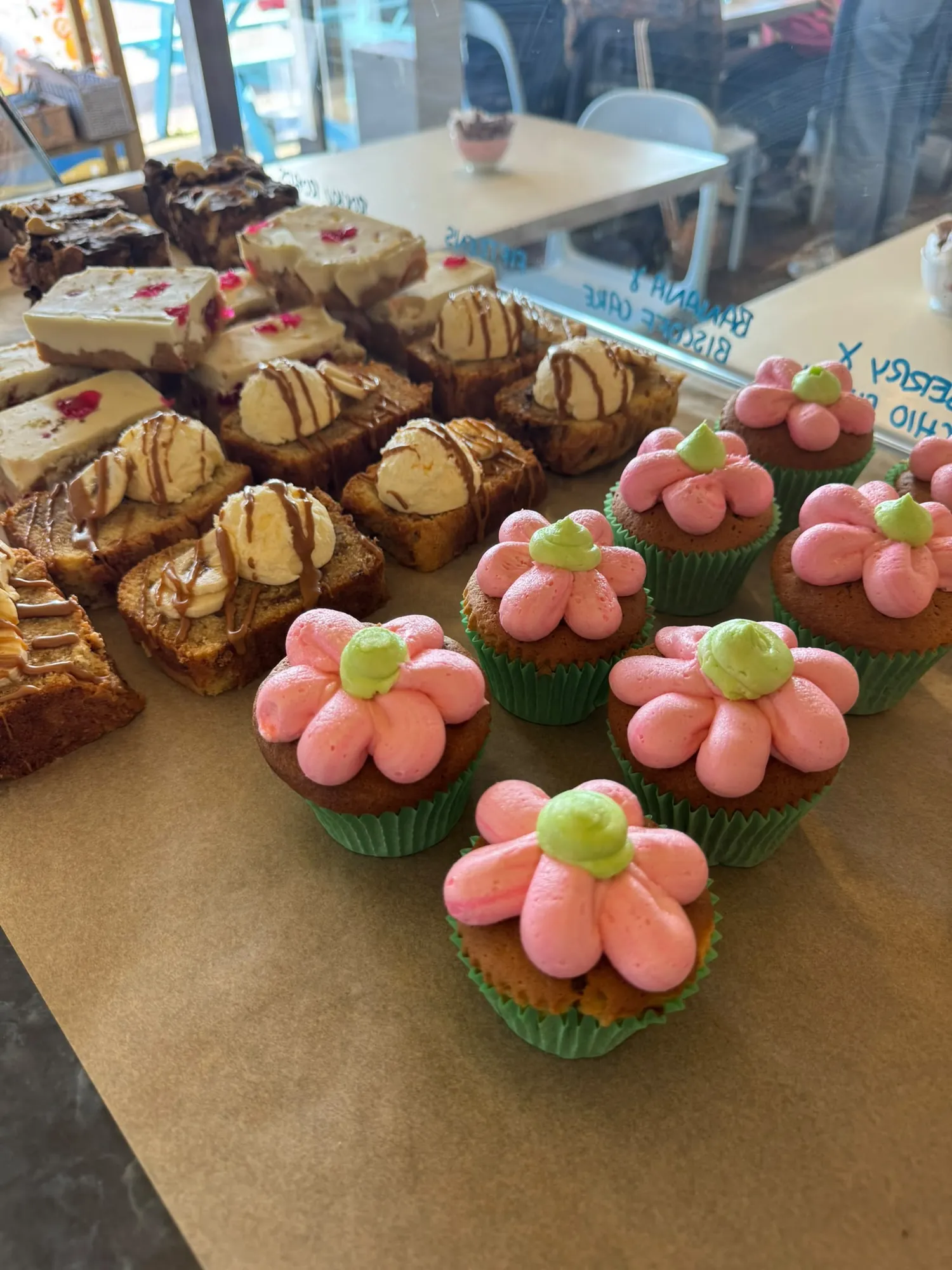 Flower-topped cupcakes and traybakes on the counter