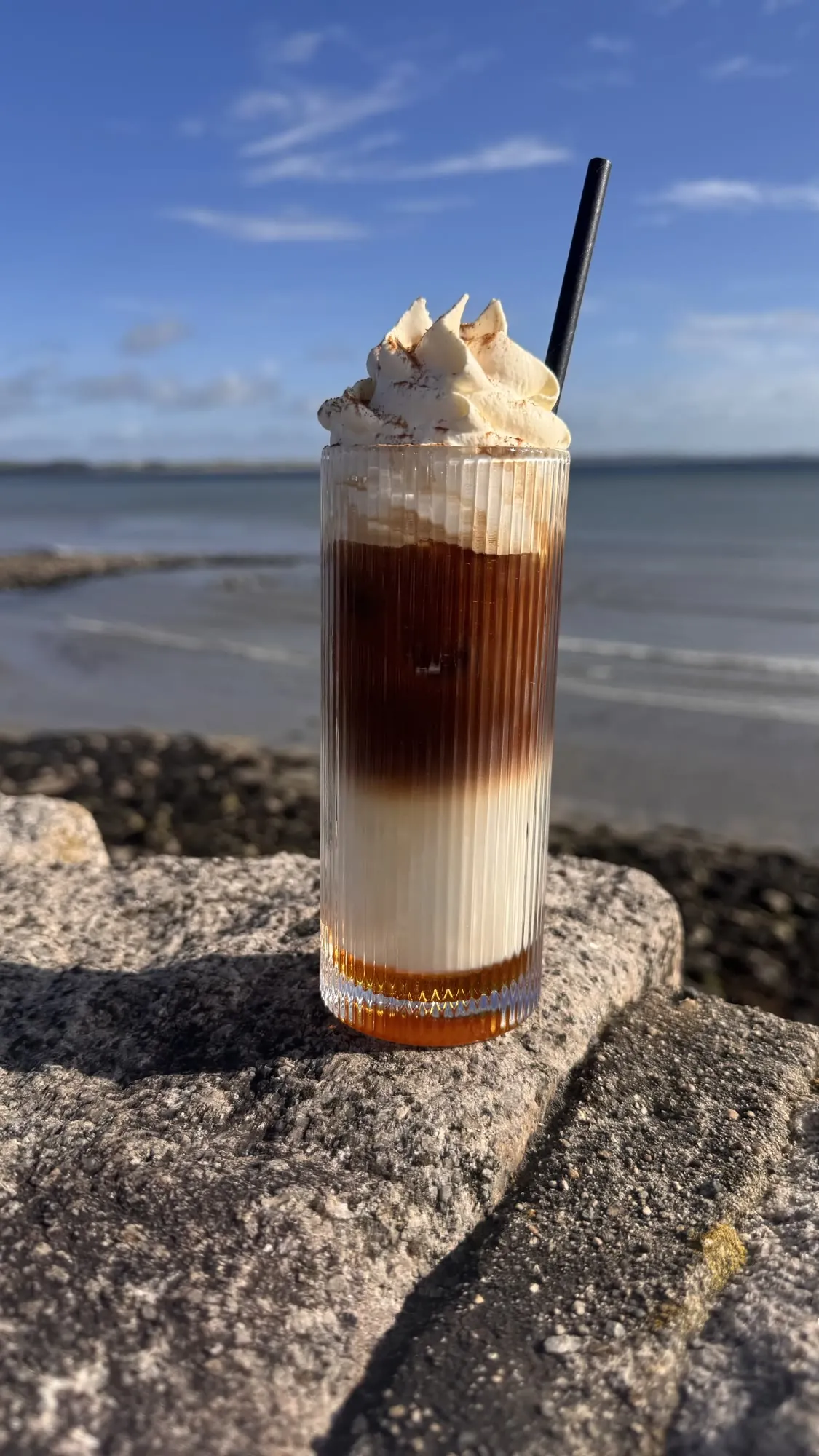 Iced coffee topped with cream on the sea wall