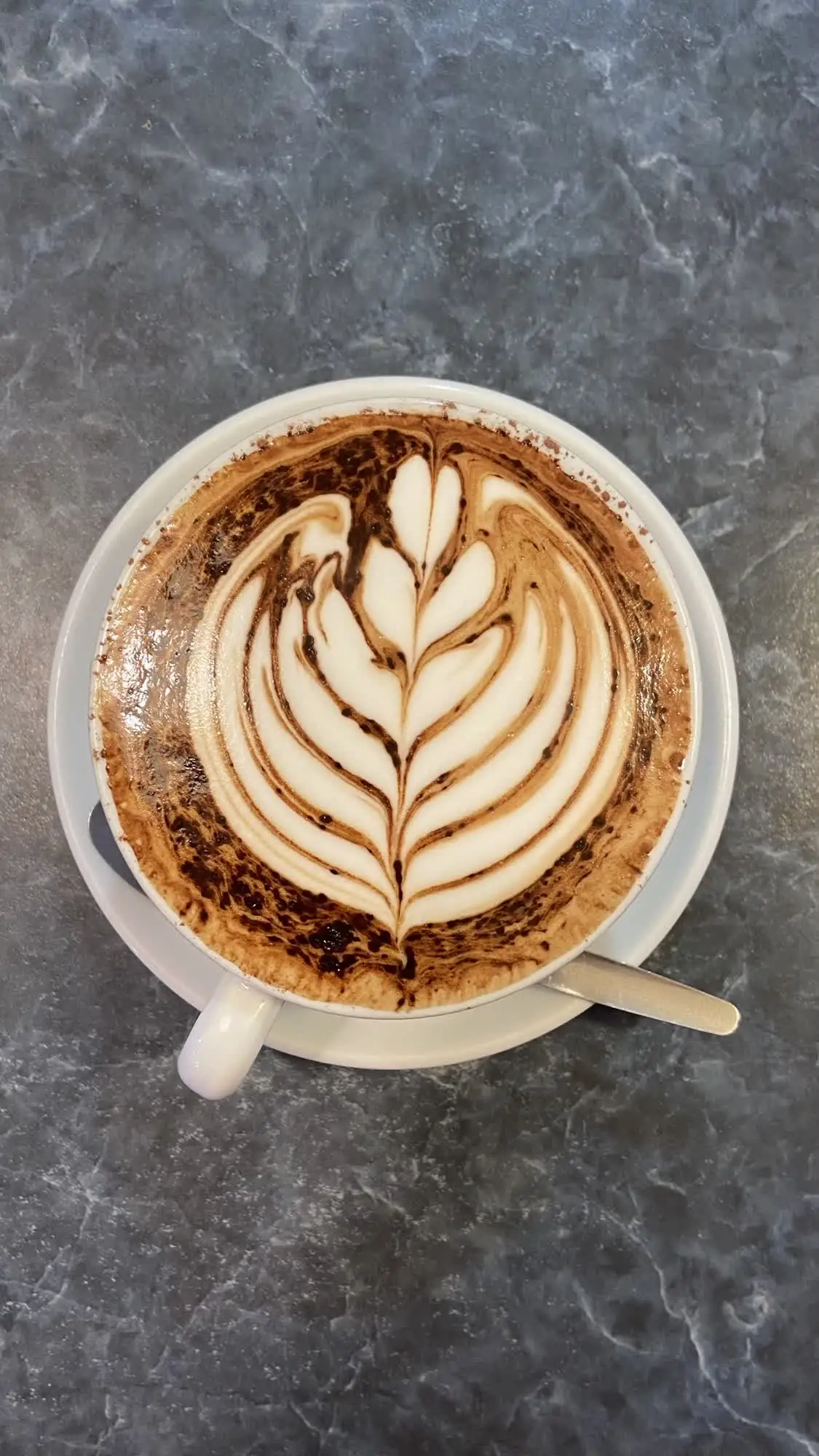 Latte with leaf art on a marble table